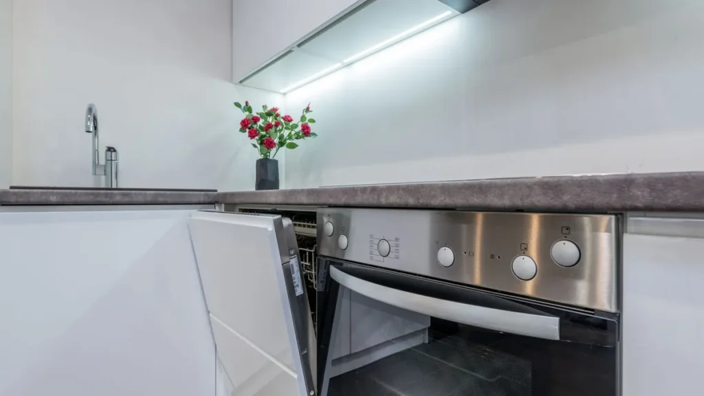 A dishwasher installed between white kitchen cabinets