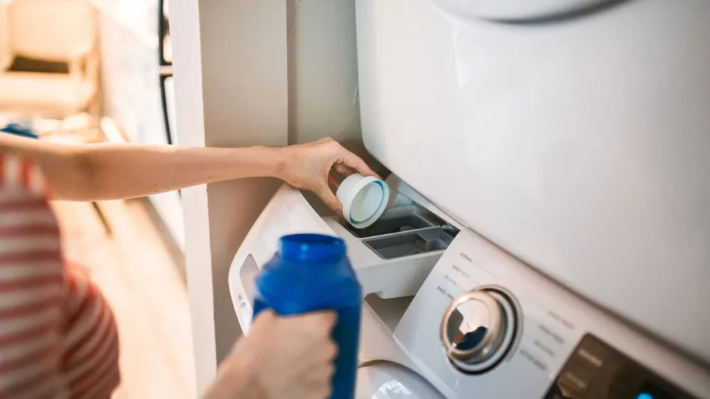 A top-load washing machine next to a dryer in a clean home laundry room
