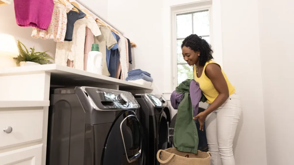 A white top-load washing machine with its lid open in a bright home laundry room